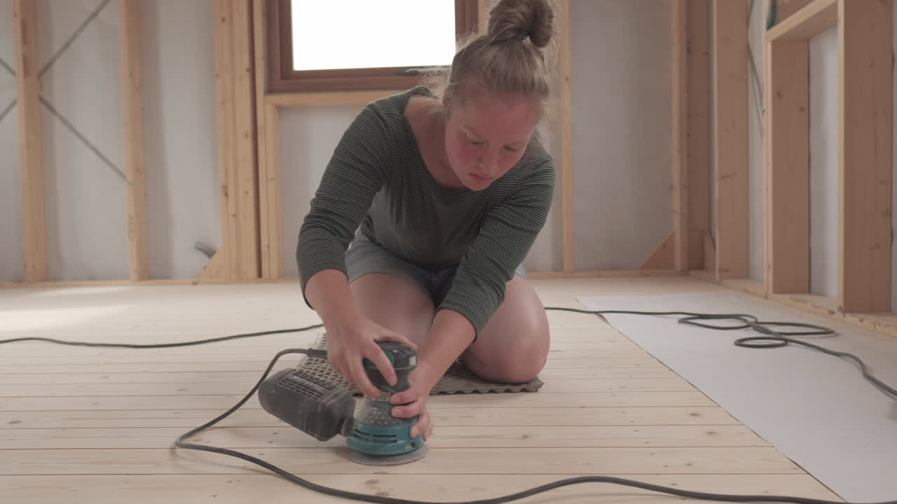 Woman sanding down a wooden floor