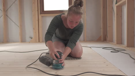 woman sanding down a wooden floor