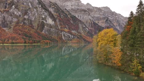 autumn colors reflect on the calm waters of klöntalersee, surrounded by swiss mountains
