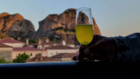 levantando una copa de vino con montañas y casas en el fondo
