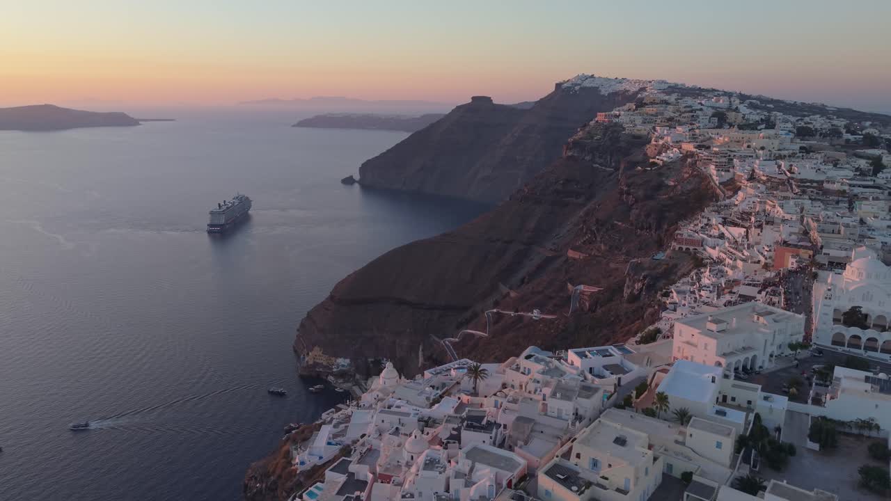Fånga essensen av en sommareftermiddag på Santorini. Denna bild visar calderans djupblå vatten, majestätiska kryssningsfartyg och de vita husen vid klipporna som glöder i varmt, gyllene ljus.