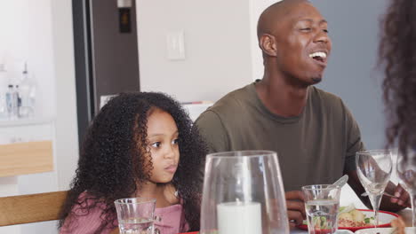 Family-Sitting-Around-Table-At-Home-Enjoying-Meal-Together