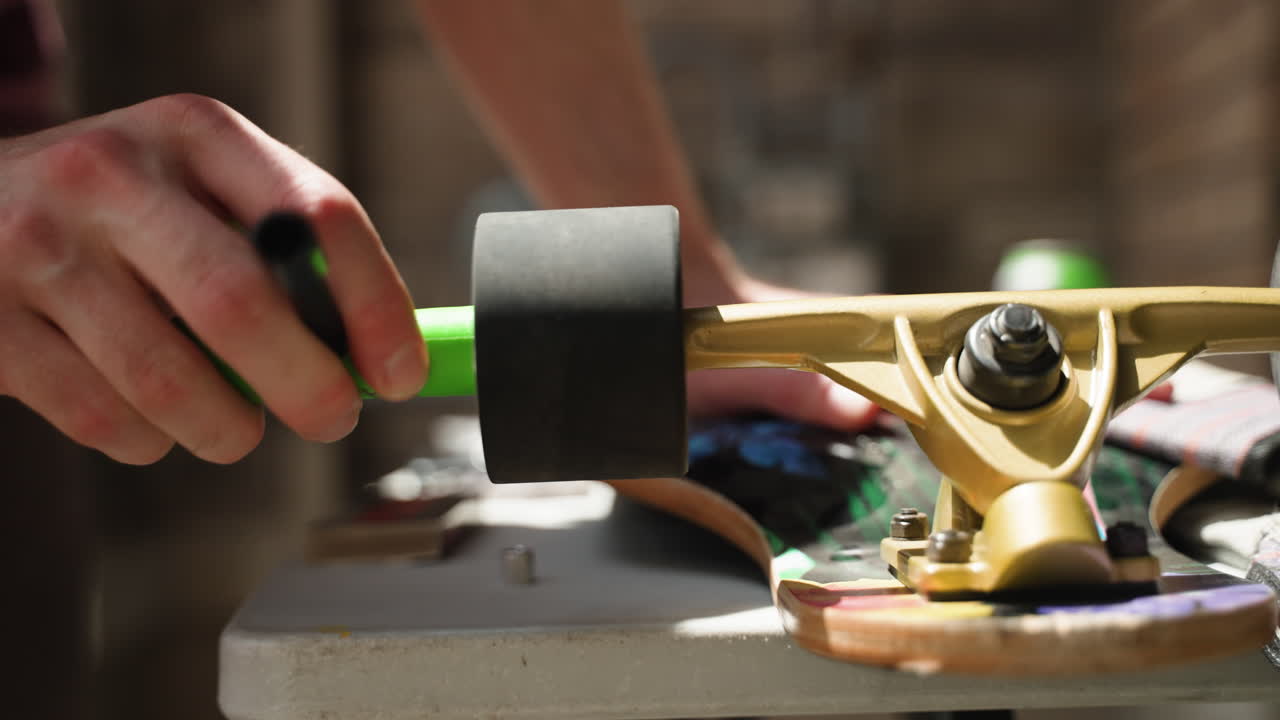 manos del hombre mientras usa una herramienta para desenroscar la rueda de longboard