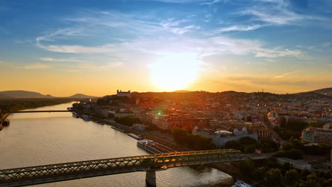 approaching the old bridge leading to the old town of bratislava, slovakia. setting sun dazzles the scenery. aerial view
