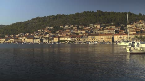 vista panorámica de los barcos atracados a lo largo de las costas de vela luka en croacia y colinas en el fondo