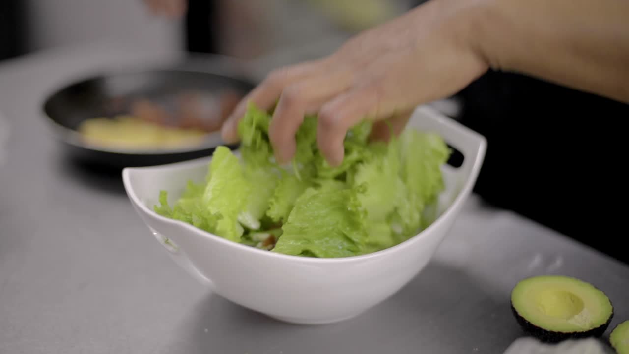 Woman chef cook preparing a salad adding chopped bacon at a local restaurant diner cafe in Mexico latin america