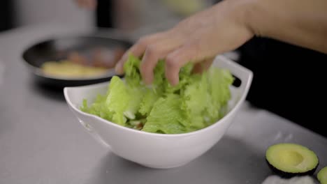 woman chef cook preparing a salad adding chopped bacon at a local restaurant diner cafe in mexico latin america