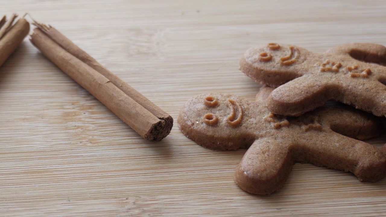 Scatto panoramico di un omino di pan di zenzero accanto a ingredienti freschi, bastoncini di cannella e radice di zenzero.