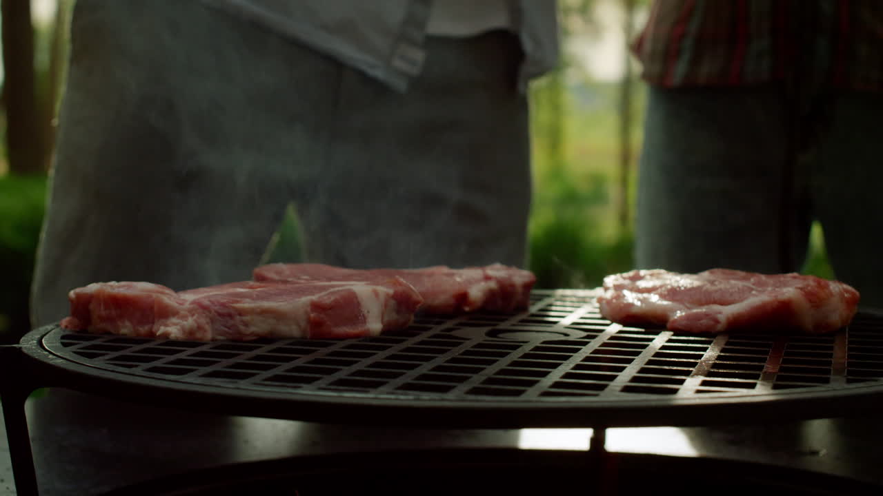 셰프가 밖에서 고기 조각을 그릴에 넣고 있다