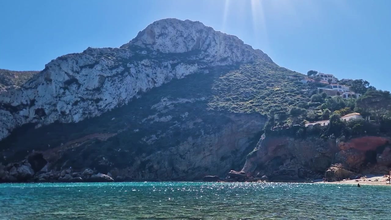 Vista panoramica sul mare con montagne lungo la costa spagnola sotto un cielo azzurro e limpido.