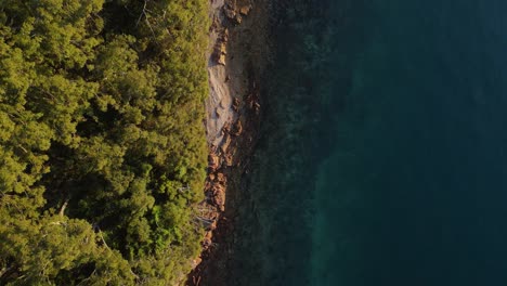 High-revealing-view-of-a-rugged-coastal-headland-next-to-tropical-blue-swimming-area