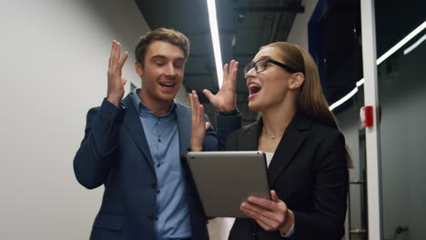 Smiling-workers-checking-tablet-report.-Impressed-business-people-discussing