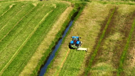 aerial view of a tractor mowing a field with a canal in the middle