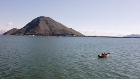 AERIAL---Boat-ride-on-beautiful-Lake-Skadar,-Montenegro,-rising-shot-pan-left