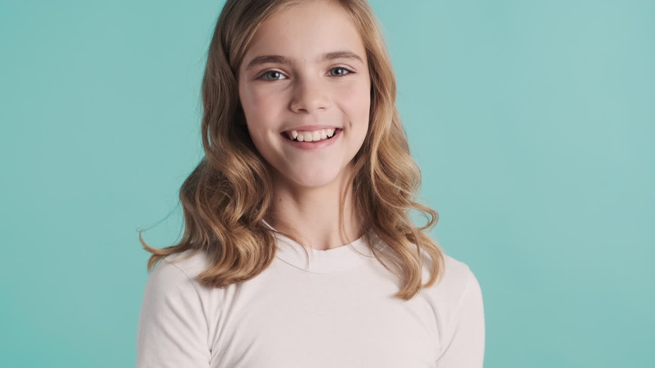 Teenage Caucasian girl in pijamas tossing an apple in her hand and smiling.