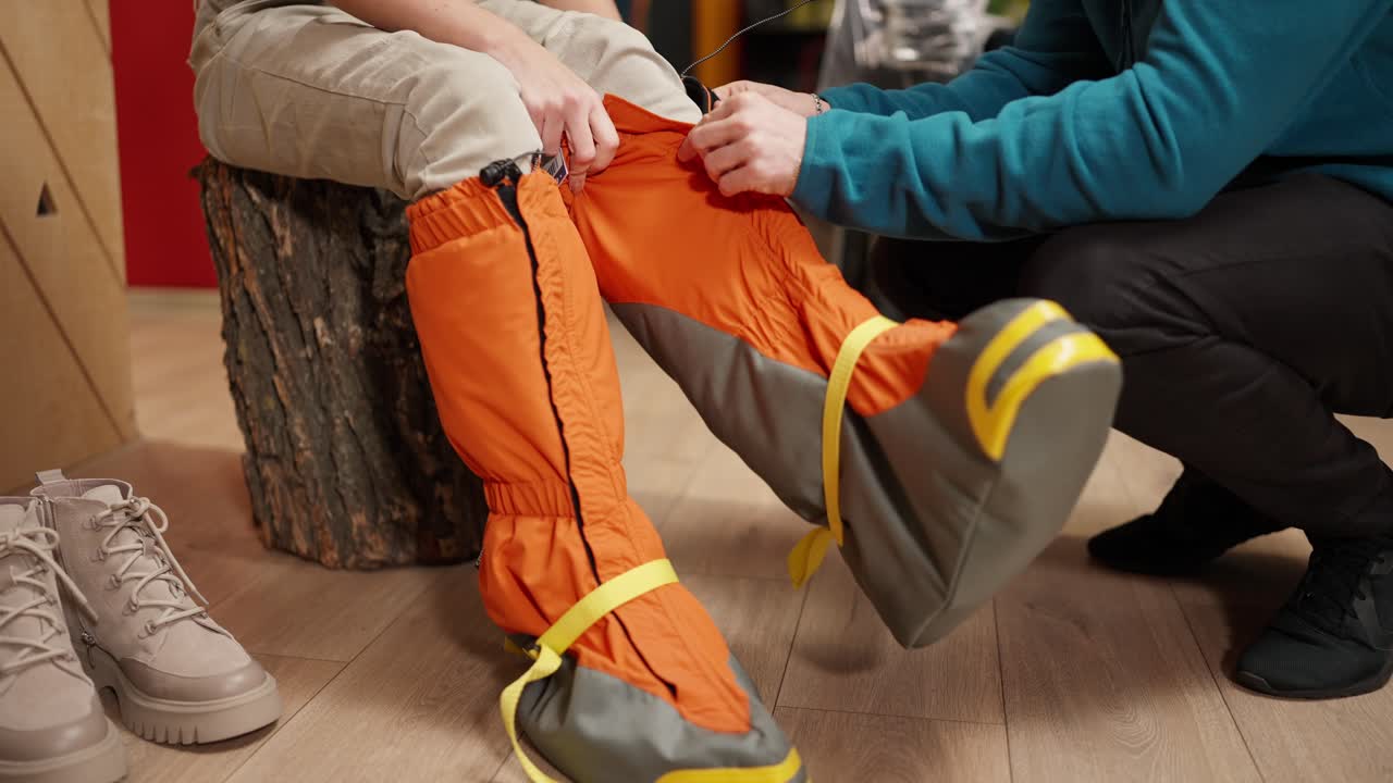 comprador en una tienda de deportes intentando grandes botas de nieve, equipos para escalar, esquí, senderismo