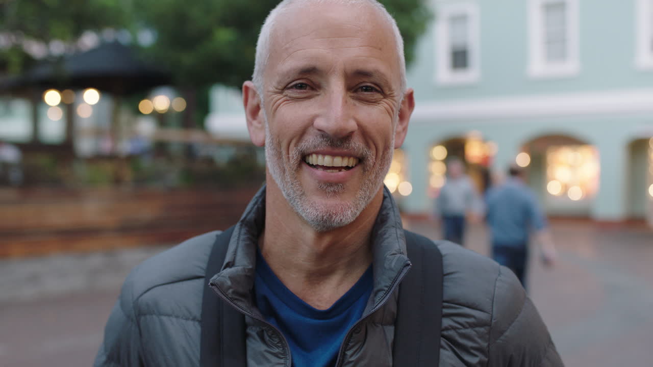 ritratto ravvicinato di un attraente turista caucasico maturo che guarda la telecamera sorridendo sullo sfondo urbano