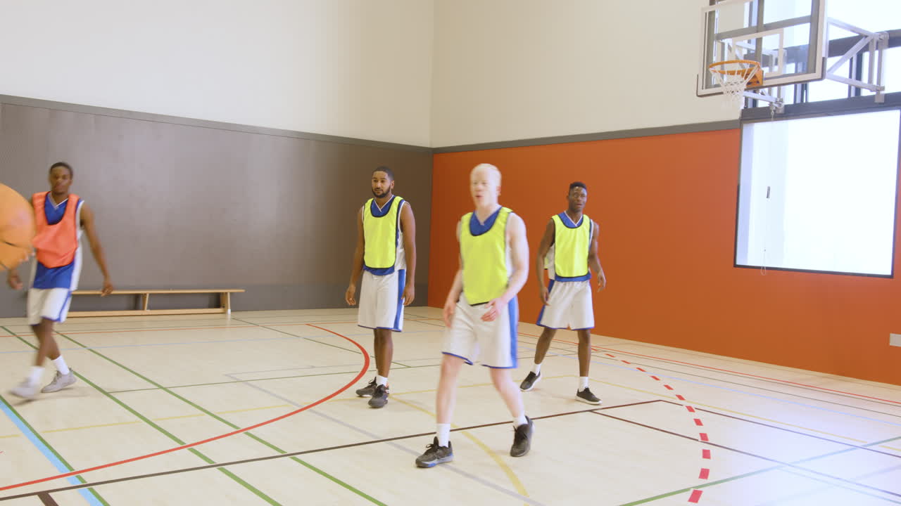 Jogadores de basquete praticando trabalho em equipe e estratégia em uma quadra de ginásio interna