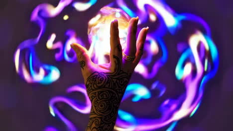 hand with henna tattoo reaching for glowing sphere