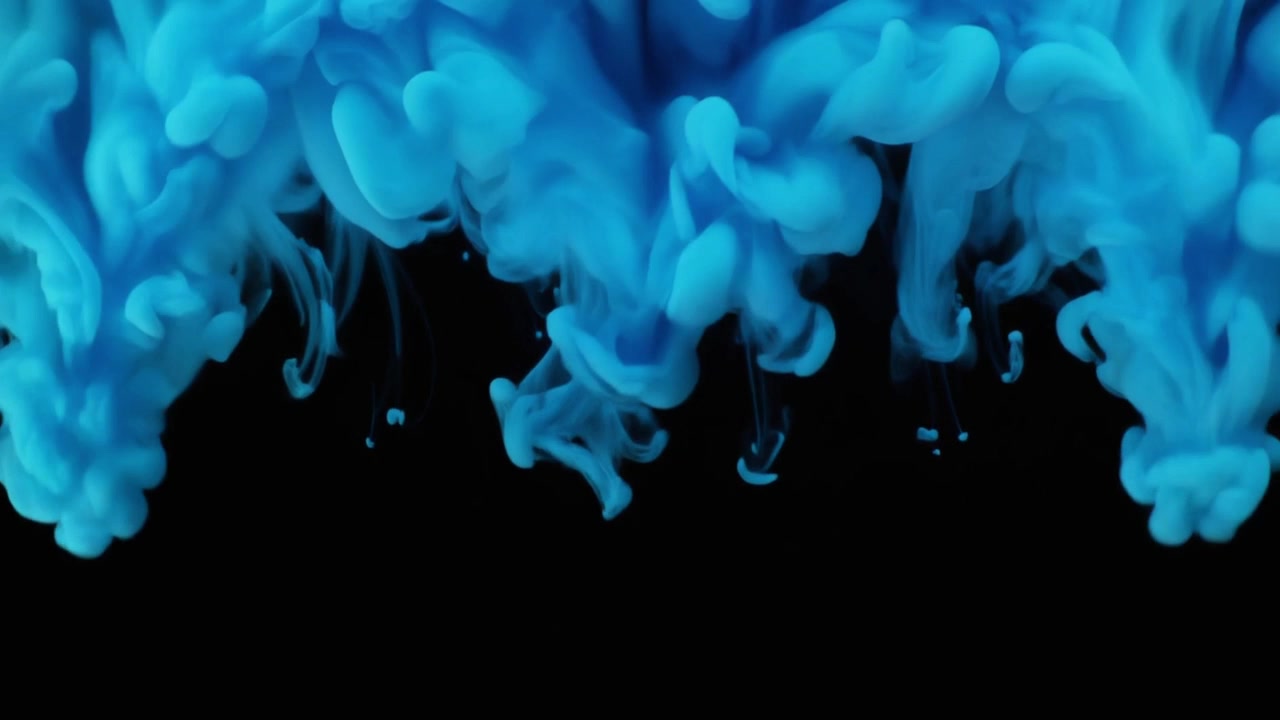 Inchiostro blu che cade e si avvolge nell'acqua su sfondo nero