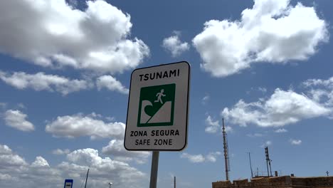 Close up shot of Tsunami Sign in Safe Zone against blue sky and clouds at ocean in Portugal