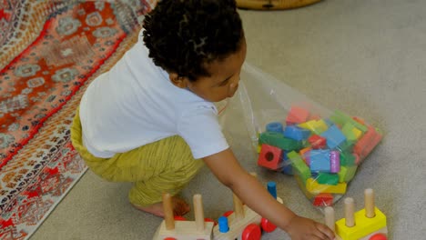 high angle view of cute little black boy playing and crouching on floor of comfortable home 4k