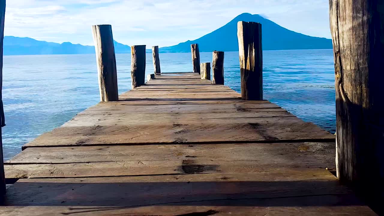 Walking on the bridge seeing the landscape of Amatitlan lake and a beautiful volcano in a sunny day with blue sky and montains.