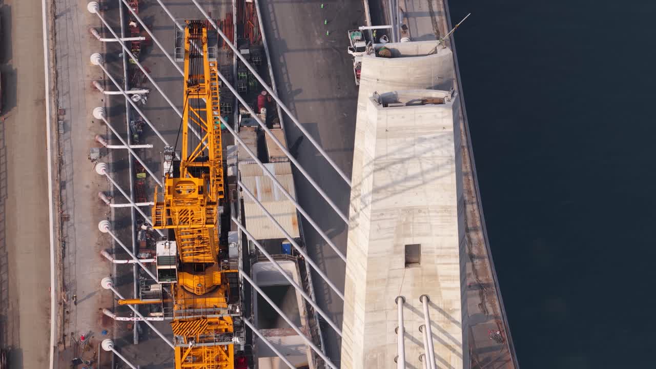Aerial view of a tower crane building a suspension bridge pylon