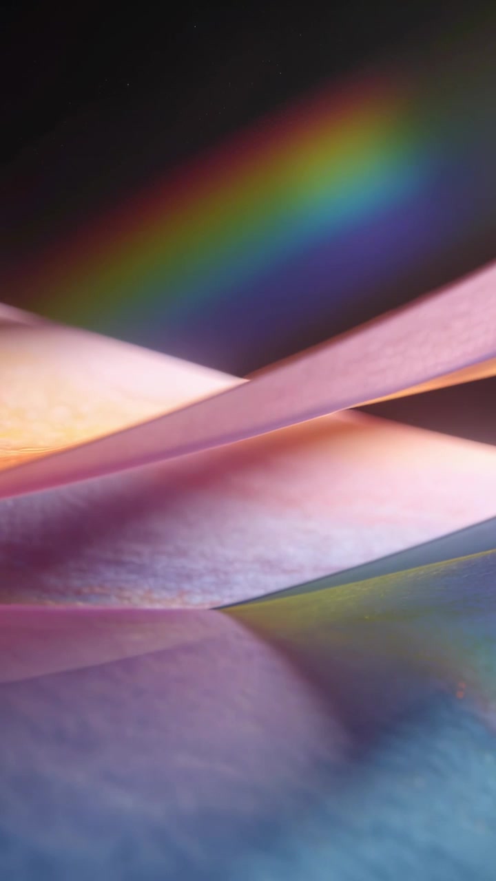 Video verticale: Spostamento di luce che spinge fogli di carta curvi a strati che si muovono in studio mostrando un arcobaleno