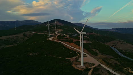 a forest and mountainous landscape view with wind turbines and a cloudy sky