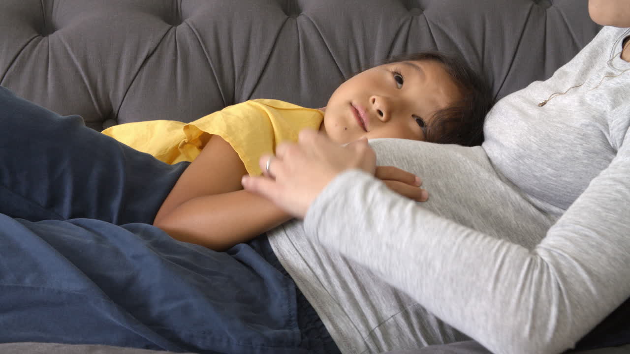 임신 한 어머니 가 딸 과 함께 소파 에서 휴식을 취하고 있다