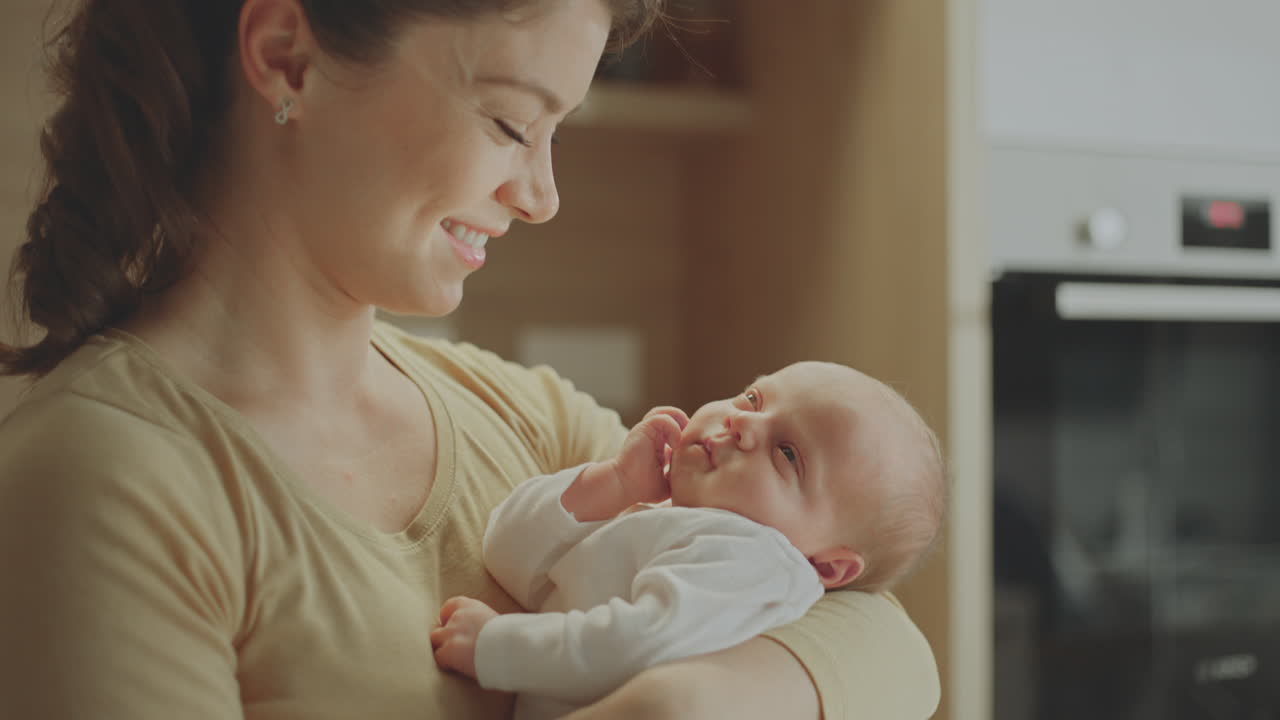 Mother holding her newborn baby in a kitchen