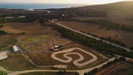 wide drone shot of an outdoor go kart race track by the beach in spain