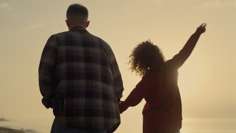 Couple-holding-hands-on-beach.-Cheerful-woman-and-man-walking-along-sea-shore