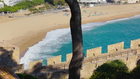 tossa de mar bay seen from the castle to the beach with coarse sand and turquoise blue sea water old walled medieval fishing village mediterranean sea