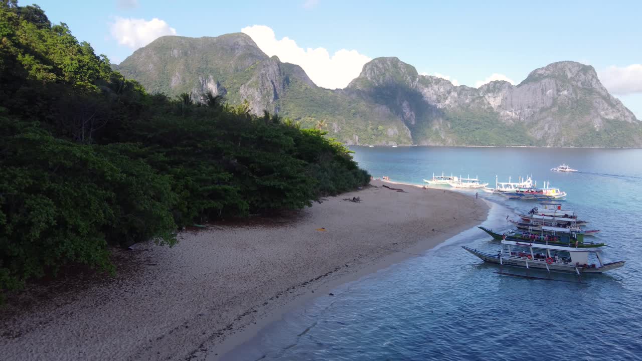 공중 : 여러 필리핀 은행 관광객 보트가 엘 니도 - 필리핀의 헬리 ⁇ 터 섬의 열대 하 ⁇  모래 해변에 정박했습니다.