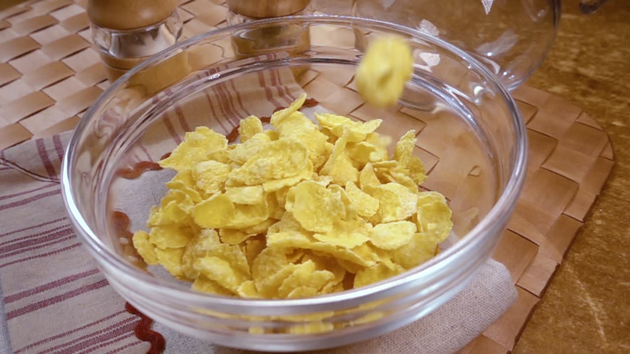 Fiocchi di mais gialli croccanti nella ciotola per una deliziosa colazione mattutina con latte. Slow motion con ripresa rotatoria.