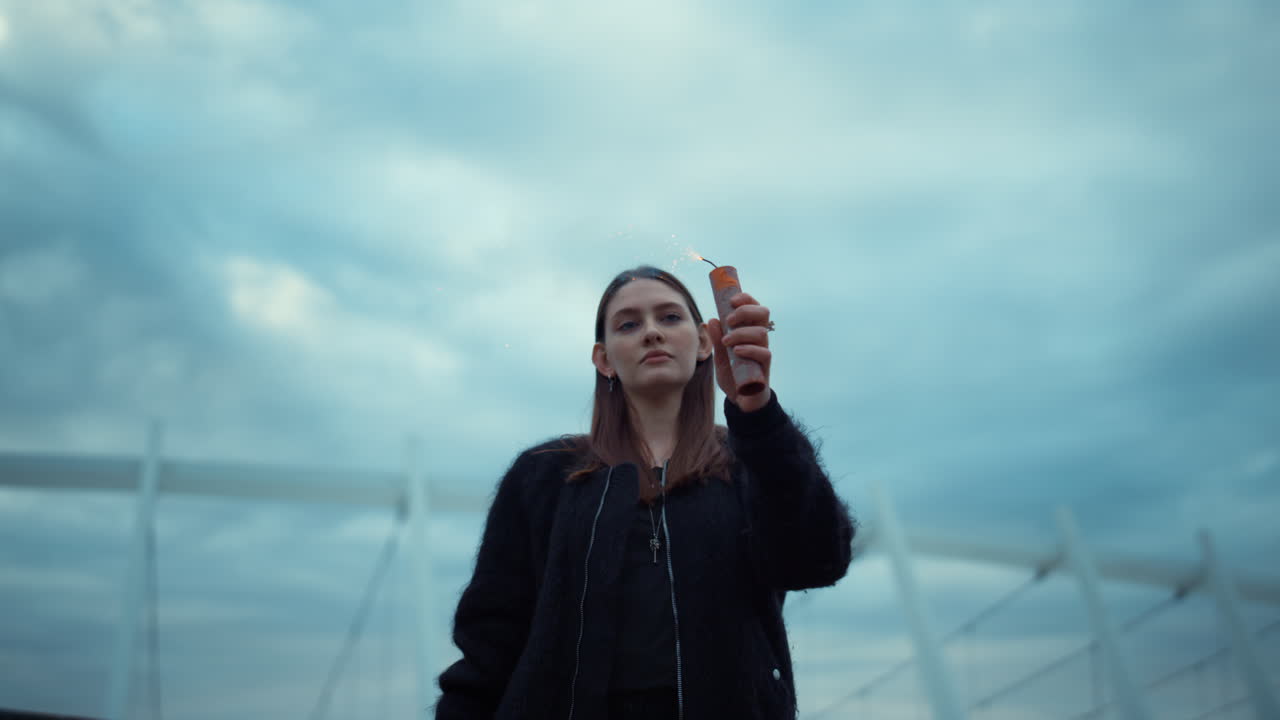 chica encendiendo una bomba de humo con un encendedor en la calle. mujer mirando una granada de humo