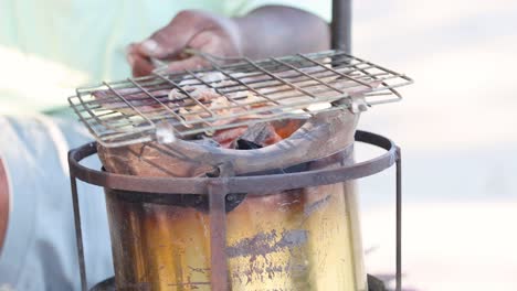 person grilling food on a charcoal barbecue