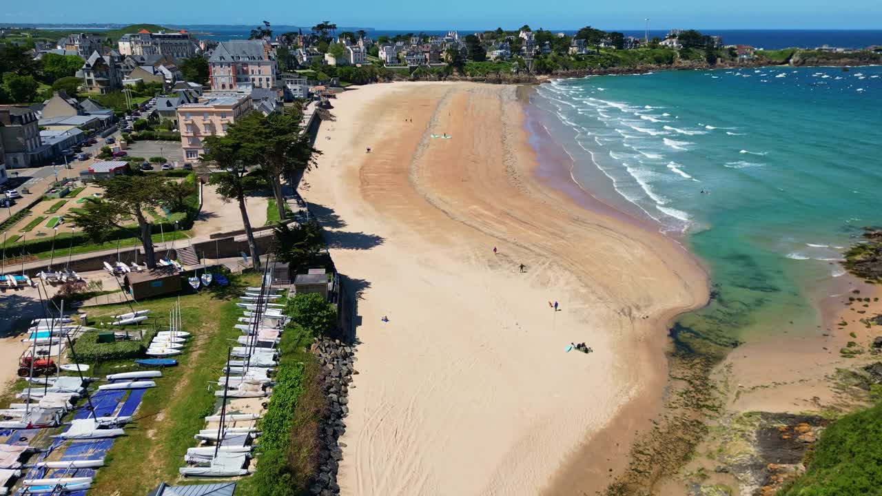 Approaching drone movement to the Saint-Lunaire Beach and boat club with clear turquoise water, Saint-Lunaire, France.