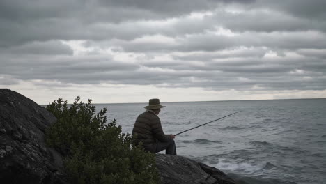 a man fishing on the coastline during cloudy weather