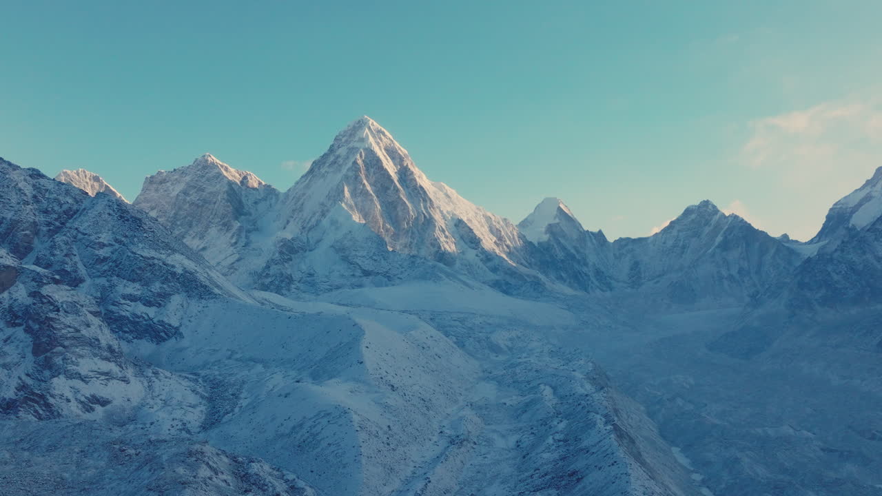 Drone view of Everest Base Camp trek in Khumbu, Nepal. Morning snowfall reveals Mount Pumori, Lobuche, and Nuptse glowing under clear blue skies as sunlight and sunrays reflect stunning Himalayas
