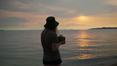 Junge-Frauen-Genießen-Eine-Frische-Kokosnuss-Mit-Einer-Wunderschönen-Aussicht-Bei-Einem-Sonnenuntergang-Am-Strand