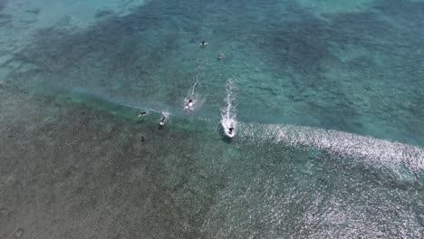 4k surfistas tomando ola de agua turquesa toma aérea