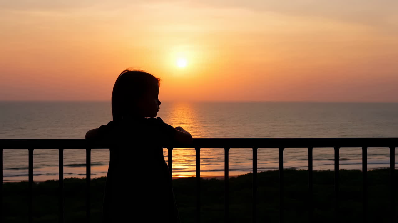 Silhouette di un bambino che osserva il tramonto sull'oceano