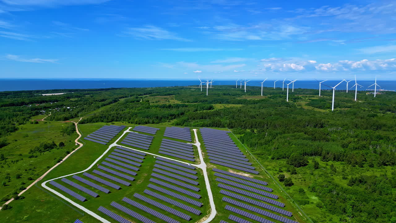 Renewable energy park with photovoltaic and windmills in green landscape, drone