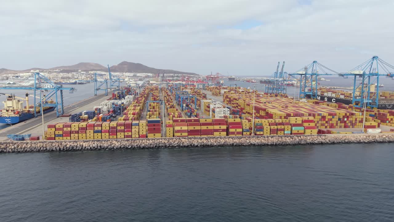 Expansive aerial view of the industrial port of La Luz in Las Palmas, featuring stacked shipping containers, cranes, and moored cargo vessels