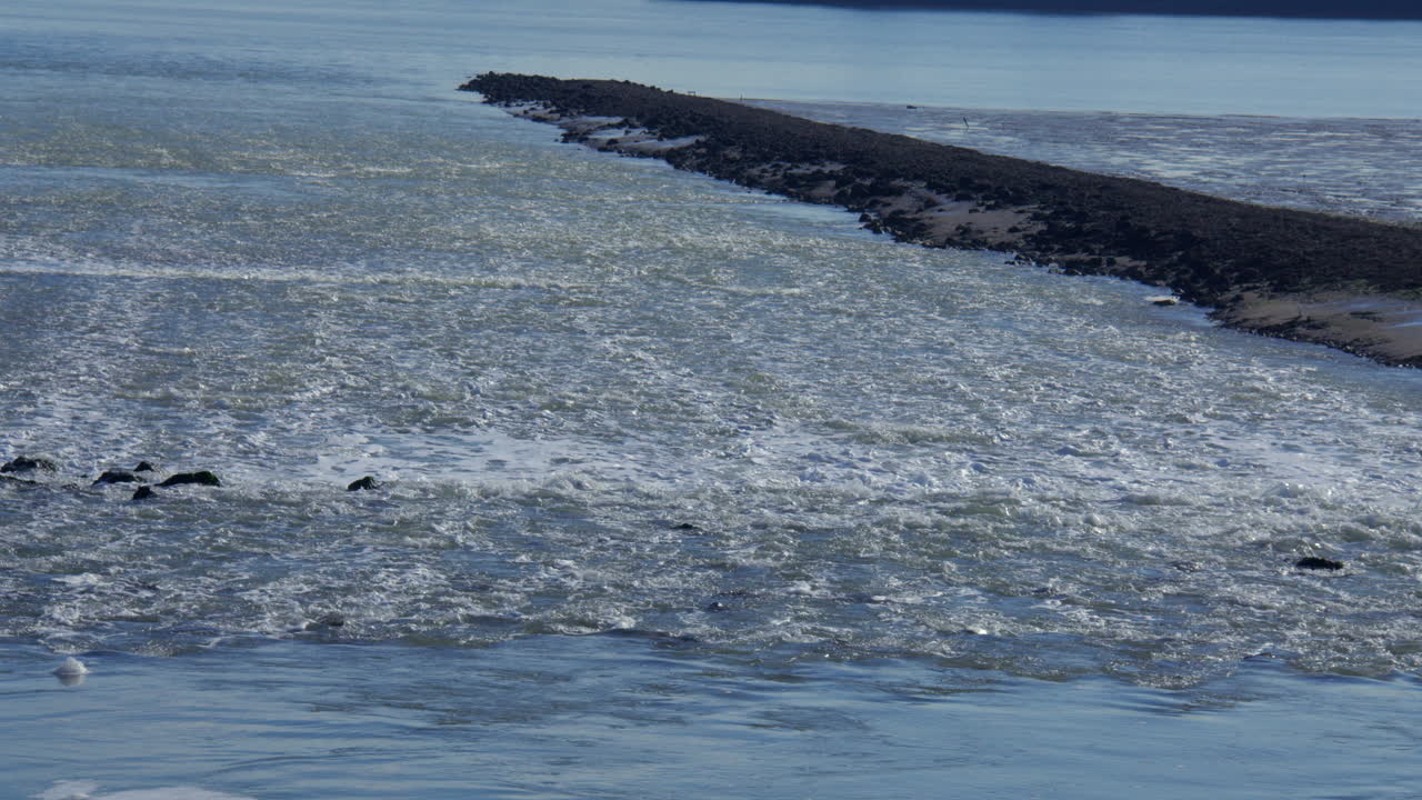 Immagine del deflusso dell'acqua dalla centrale elettrica a cogenerazione di Grain, sul fiume Medway all'Isola di Grain, accanto alla torre della batteria verde.
