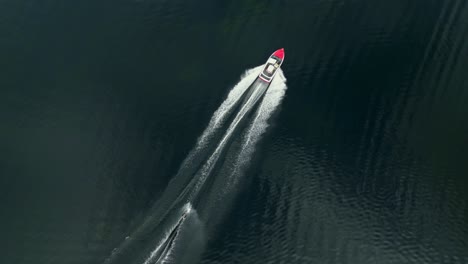 Top-down-drone-shot-of-a-person-riding-a-trick-ski-behind-a-ski-boat-on-a-lake-in-Florida