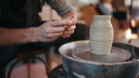 ceramist uses special tool on potter's wheel and creates a handmade clay product